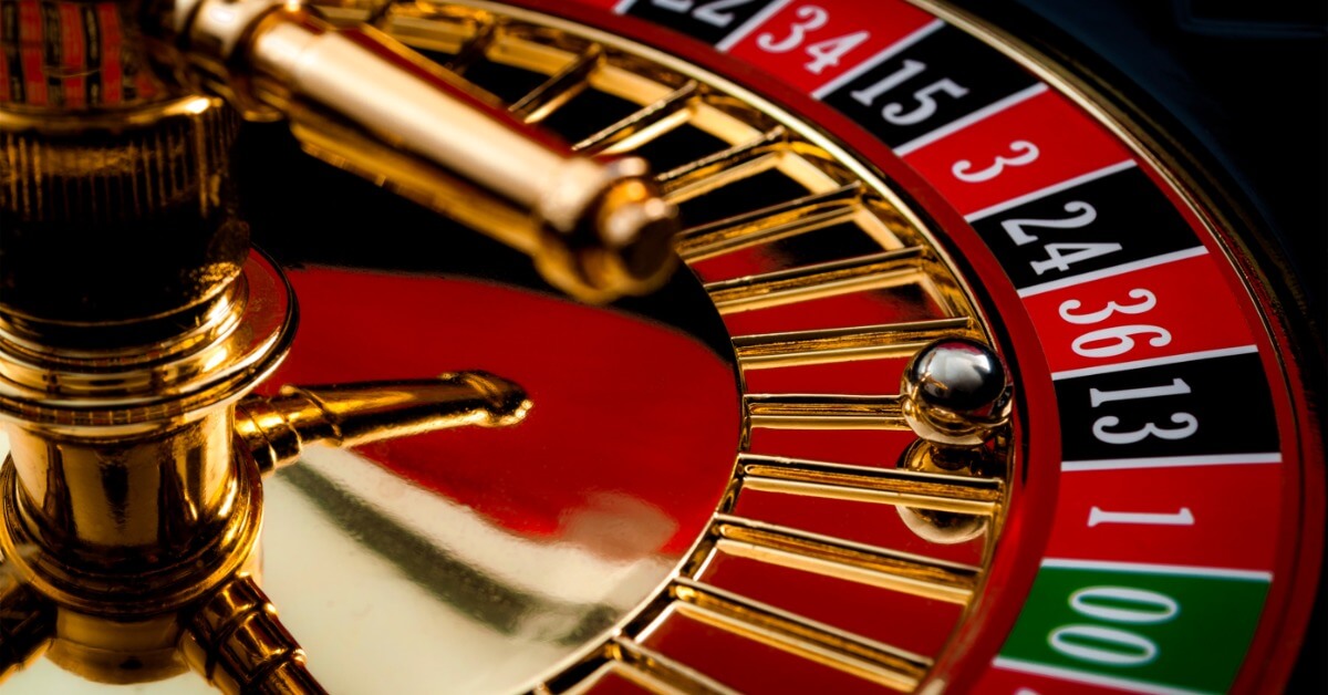 A closeup on a roulette wheel and ball. The silver ball has stopped in front of the black thirteen spot.