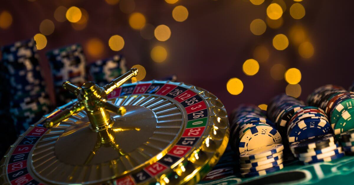 A collection of casino themed items. There is a variety of different colored poker chips and a tiny roulette wheel.