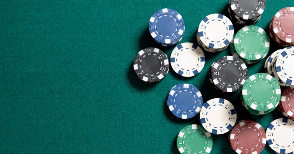 A green felt poker table surface. There are multiple different colored poker chips scattered across the table.